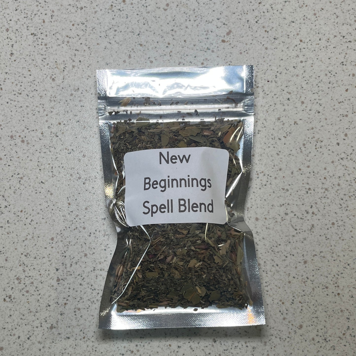 Packaged spell blend labeled 'New Beginnings' on a gray surface