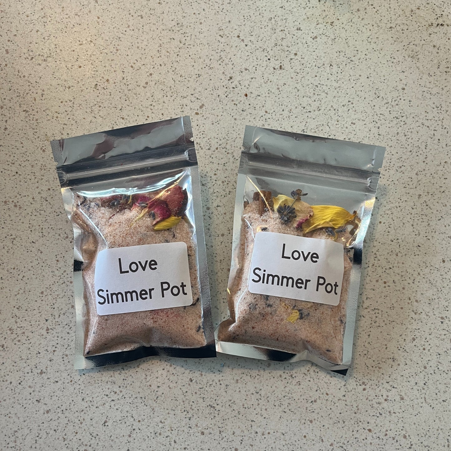 Two packages of 'Love Simmer Pot' on a textured surface