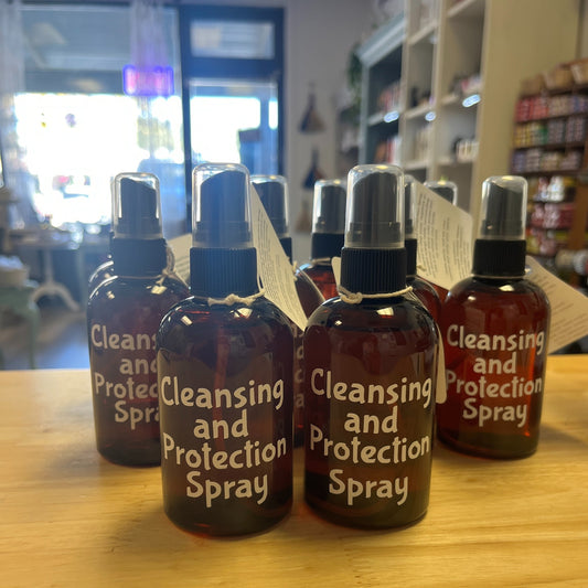 Bottles of 'Cleansing and Protection Spray' on a wooden surface with a store interior in the background.