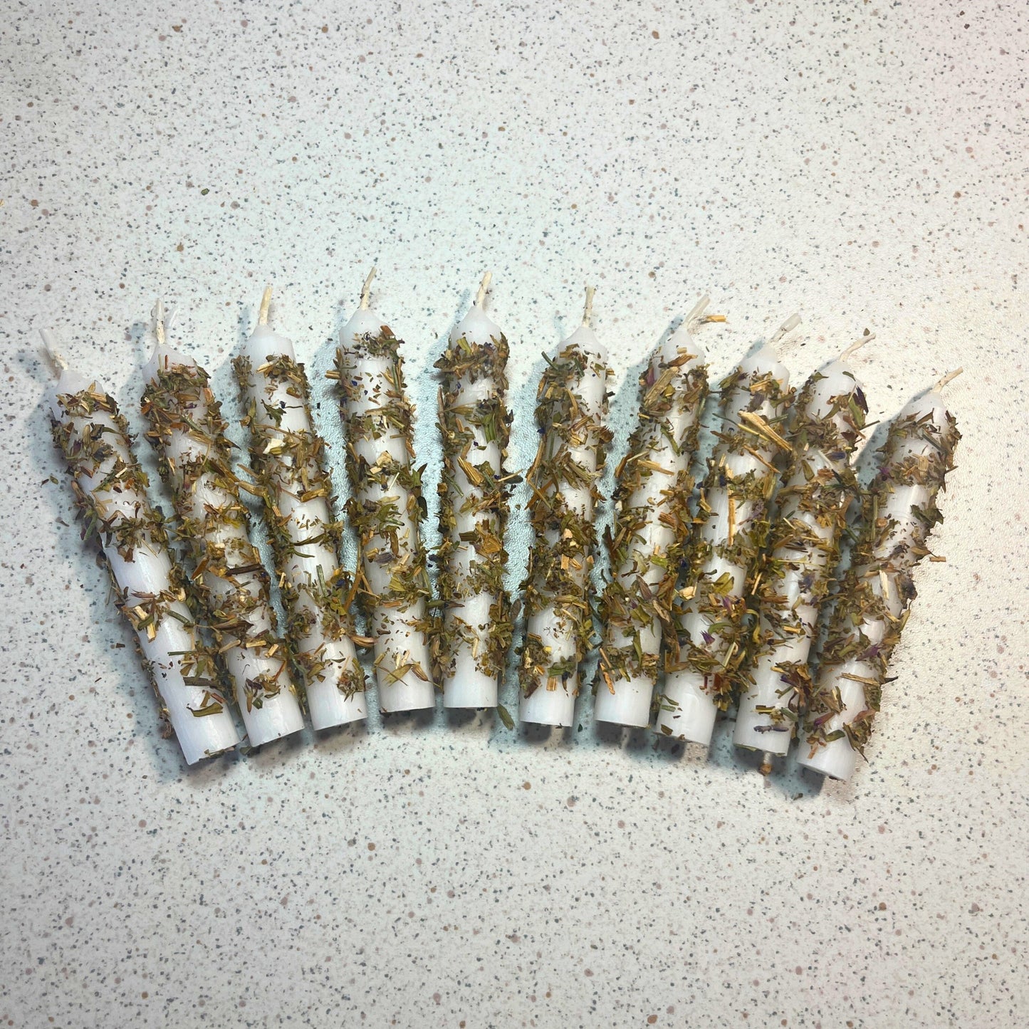 white candles dressed with herbs