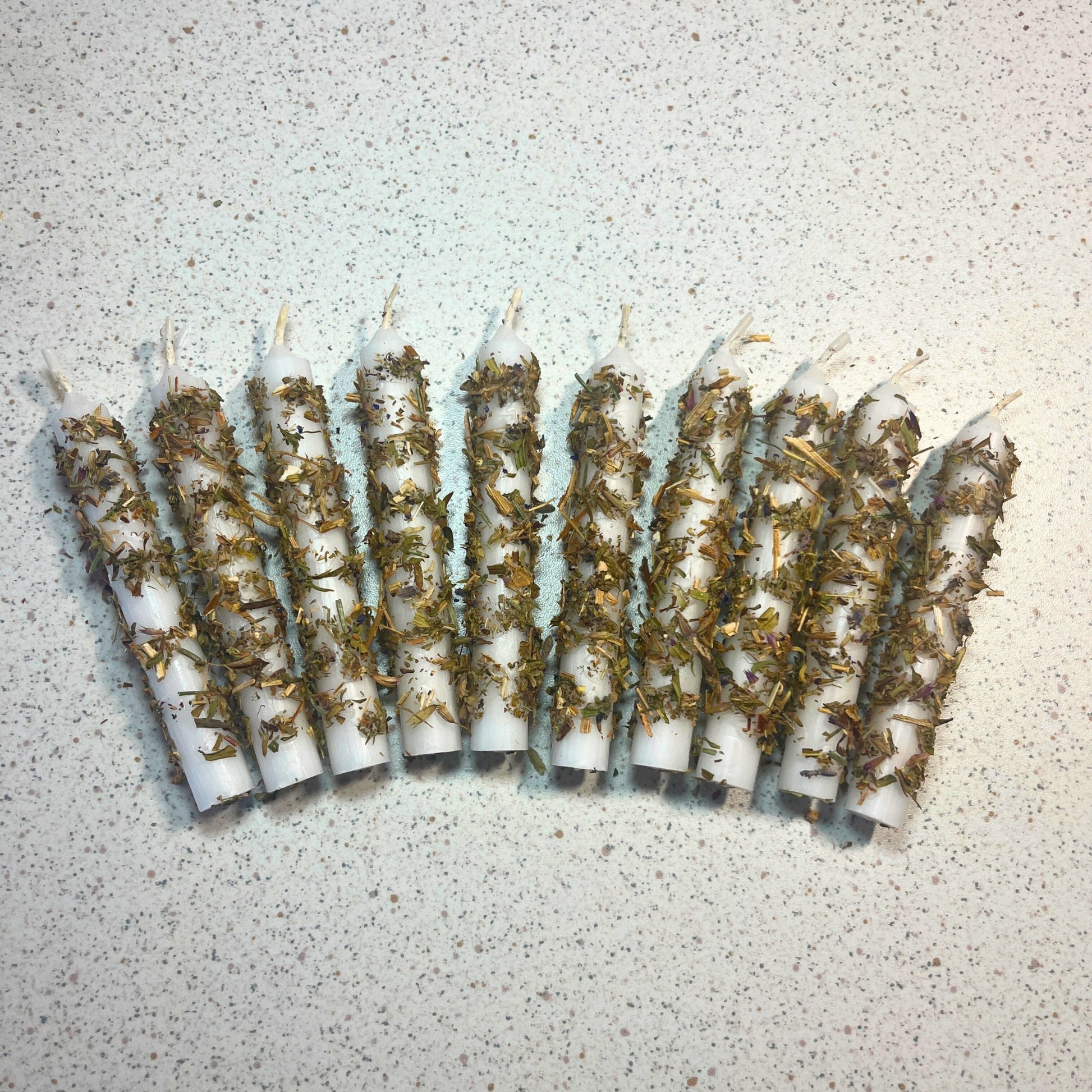 white candles dressed with herbs