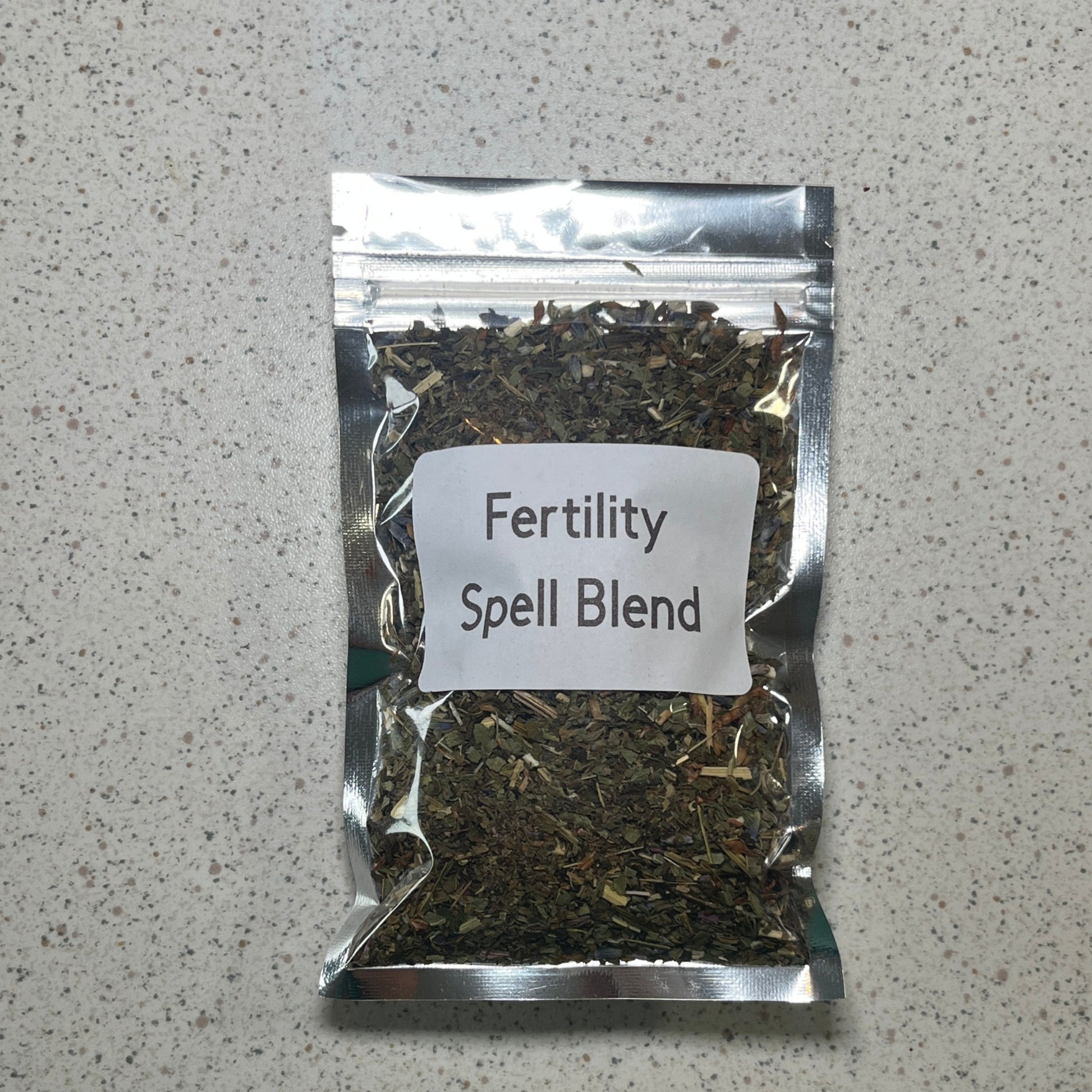 Packaged fertility spell blend on a speckled surface