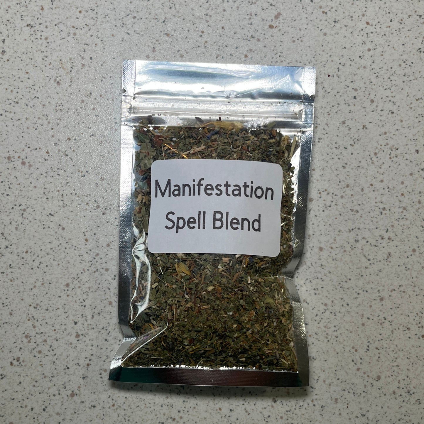 Packaged 'Manifestation Spell Blend' on a gray surface