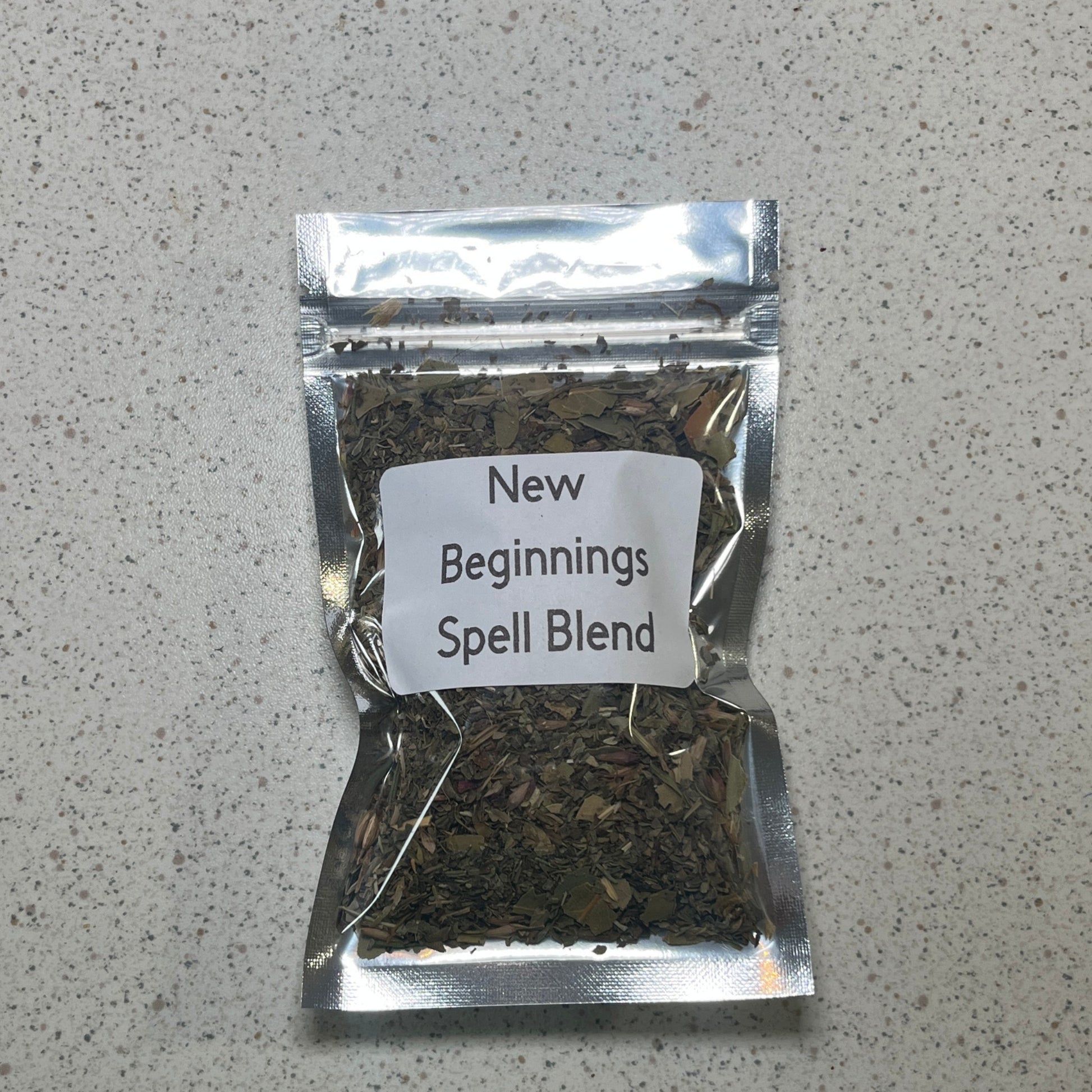 Packaged spell blend labeled 'New Beginnings' on a gray surface