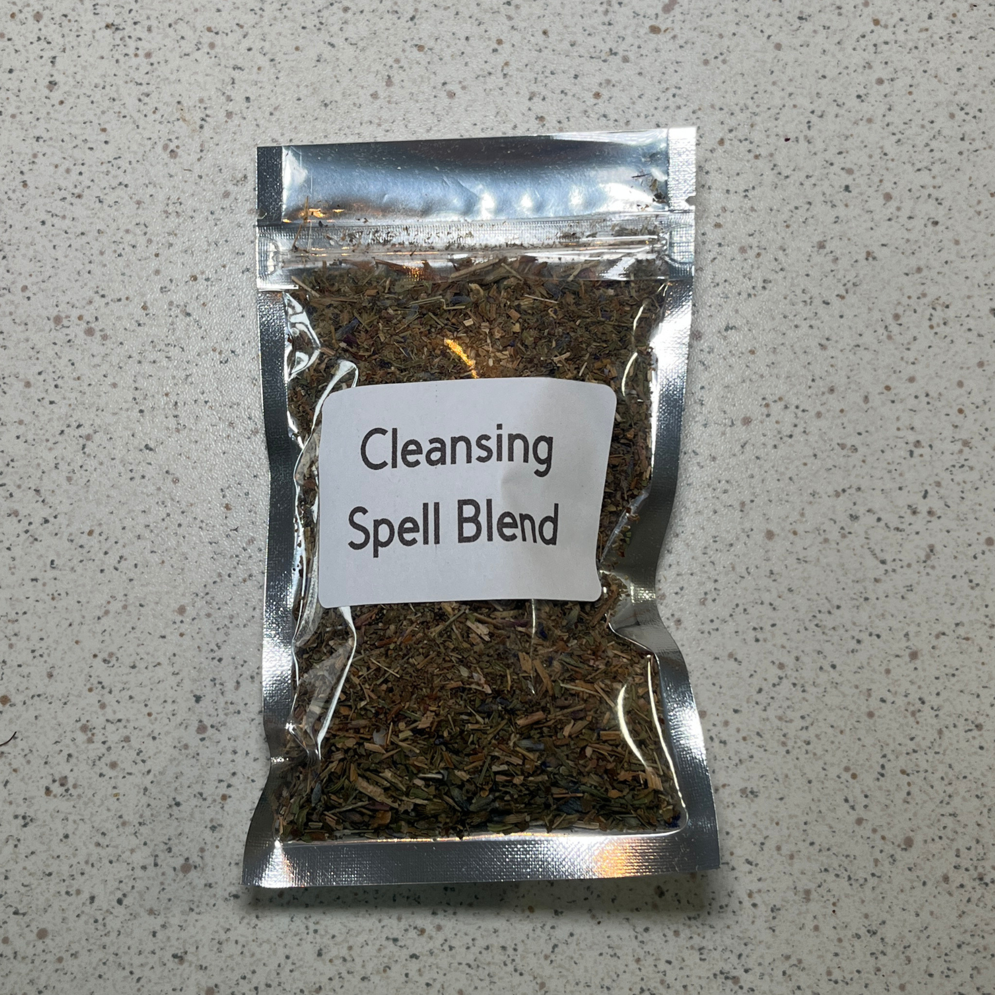 Packaged cleansing spell blend on a speckled gray surface