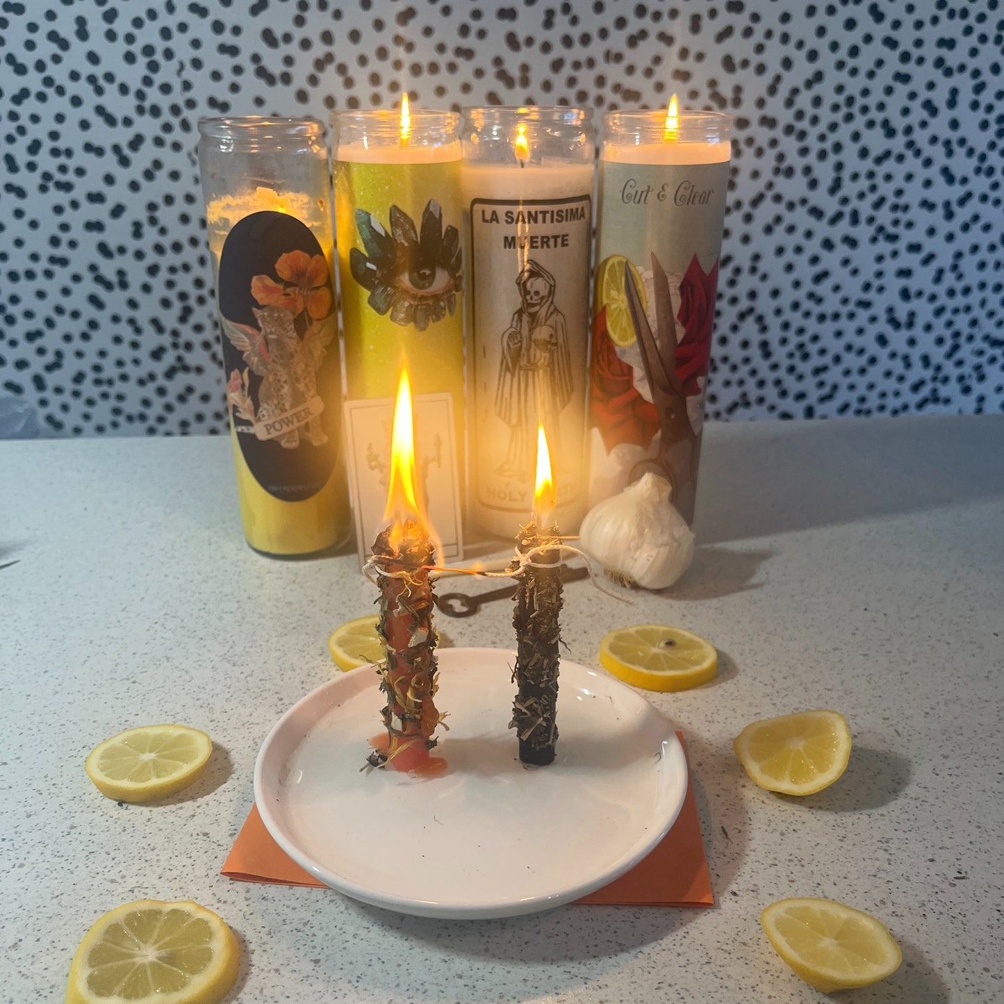 Candle holder with lit candles and lemons on a textured surface and a cord cutting in progress