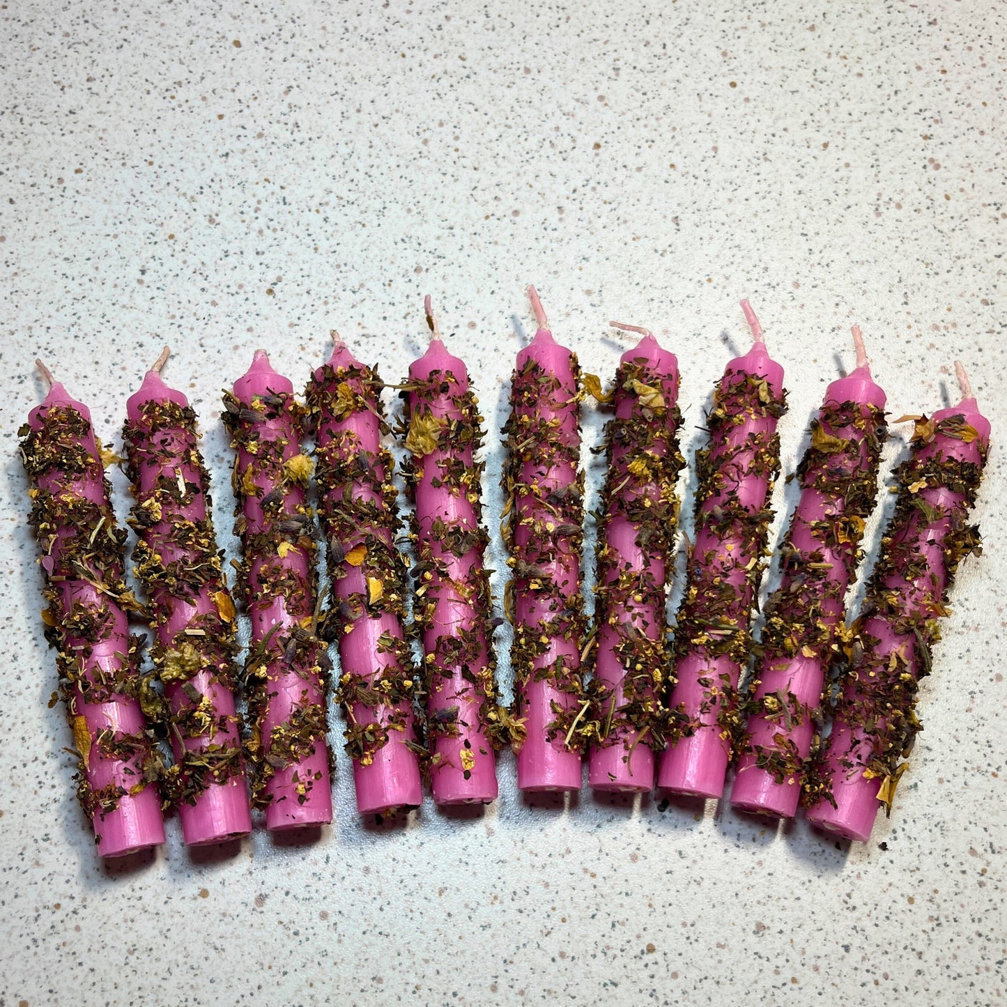 pink ritual candles dressed with herbs