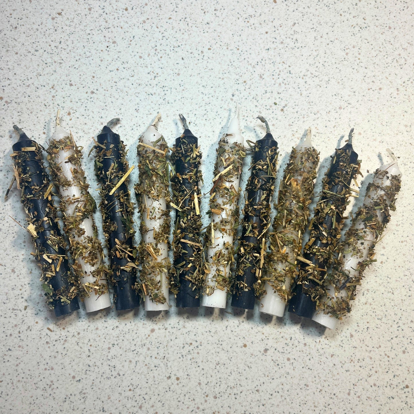 black and white candles dressed with herbs