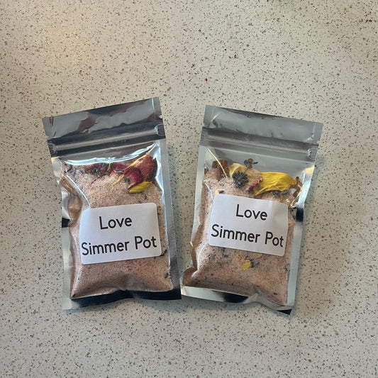 Two packages of 'Love Simmer Pot' on a textured surface