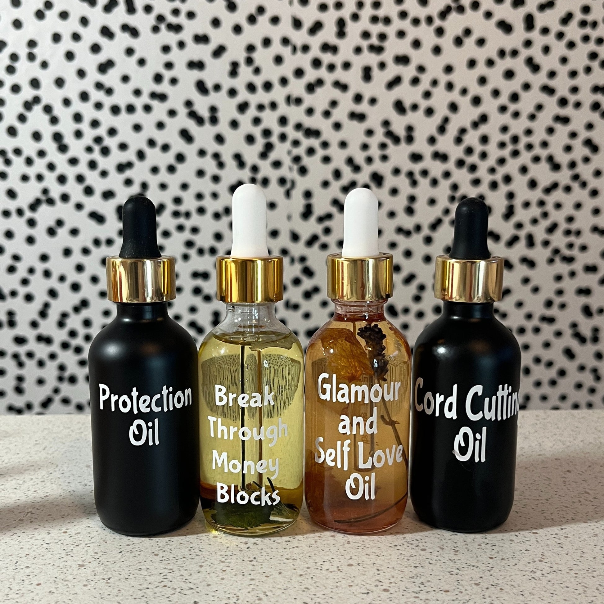 Four bottles of oils with dropper tops on a textured surface with a patterned background
